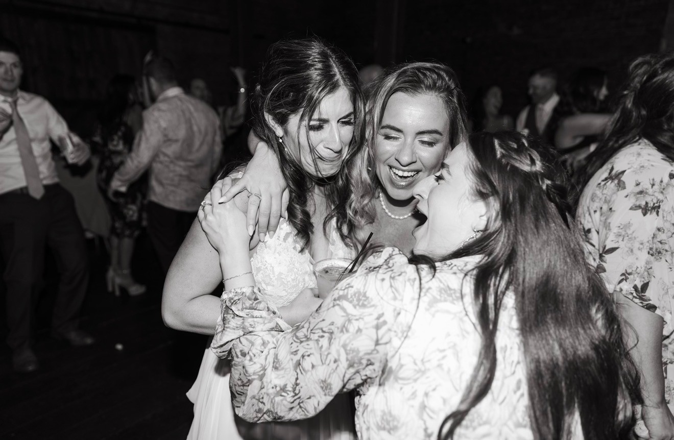 A candid black and white photo of Danielle Lampron sharing a warm, emotional hug with a grateful client.