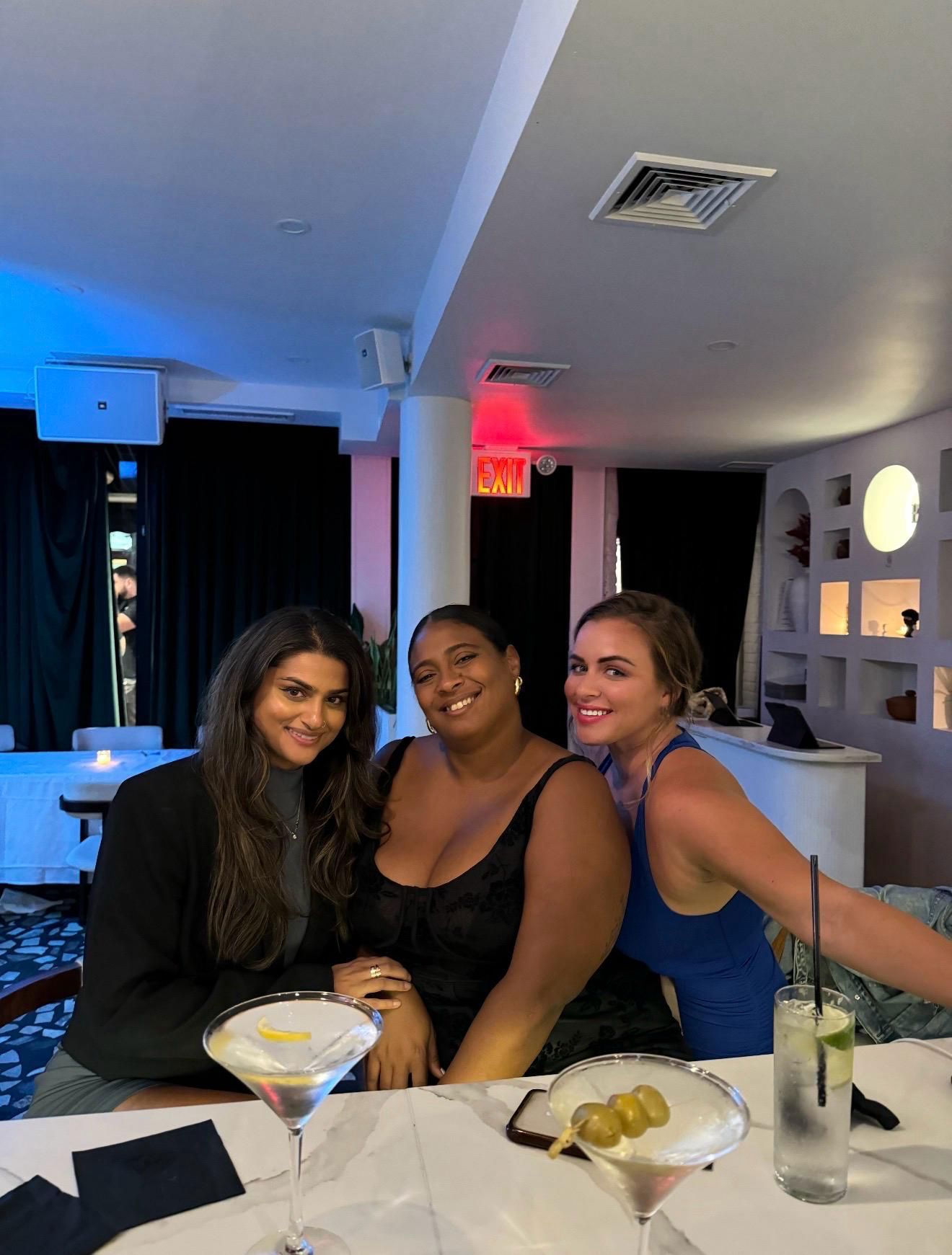 Danielle Lampron (center) smiling and enjoying an intimate luxury dinner with her clients.