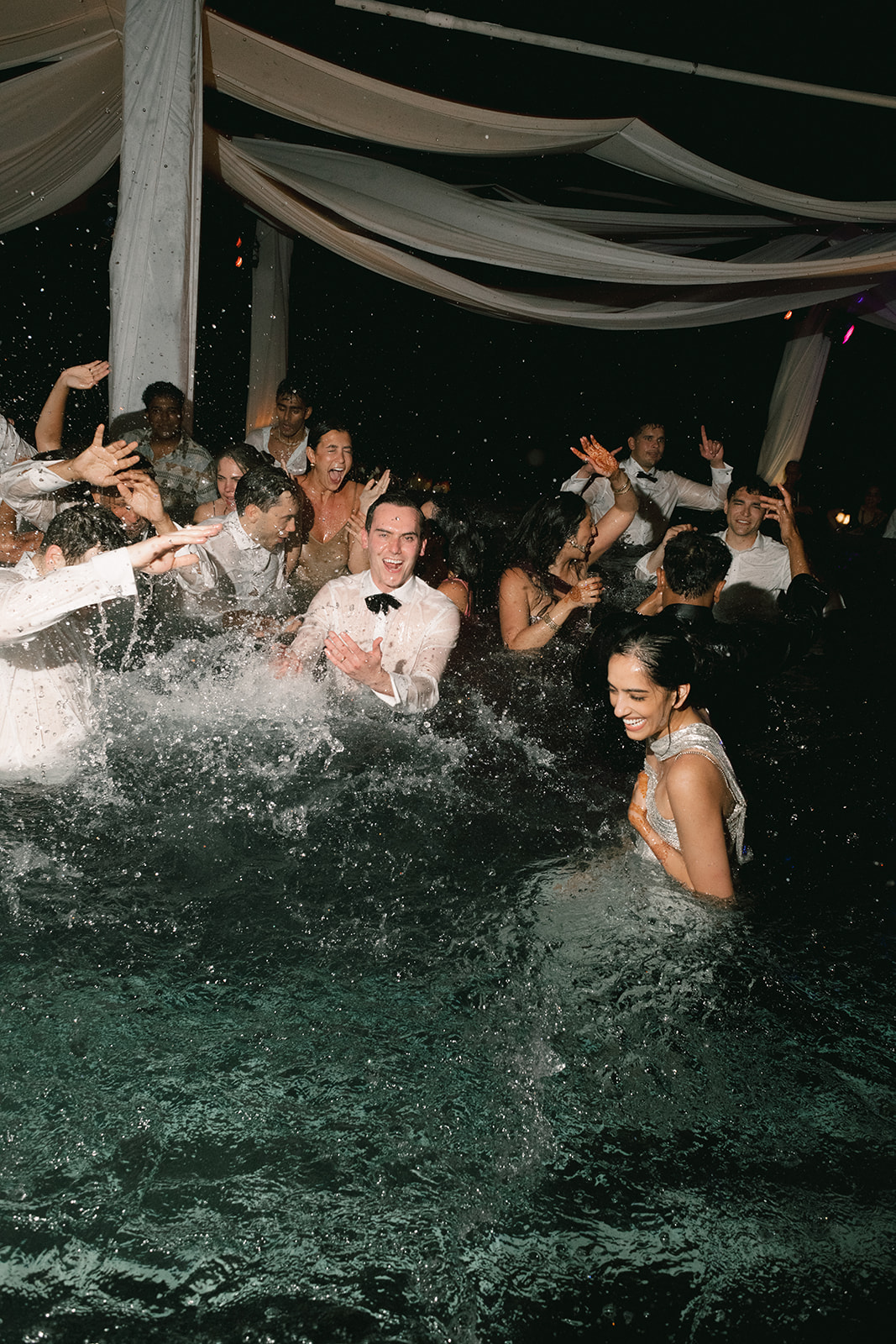 Black and white action shot of a high-energy pool after-party at a luxury resort destination.