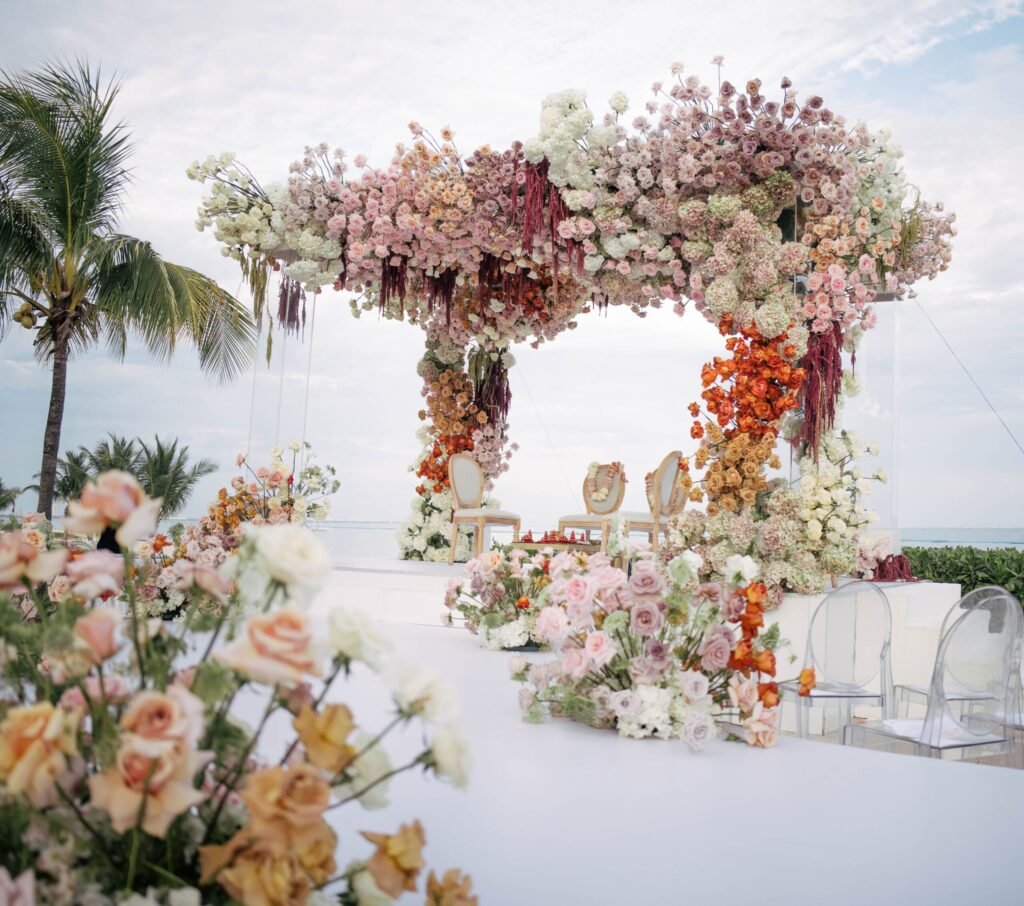 Pink and white flowers frame the ocean at an outdoor wedding ceremony