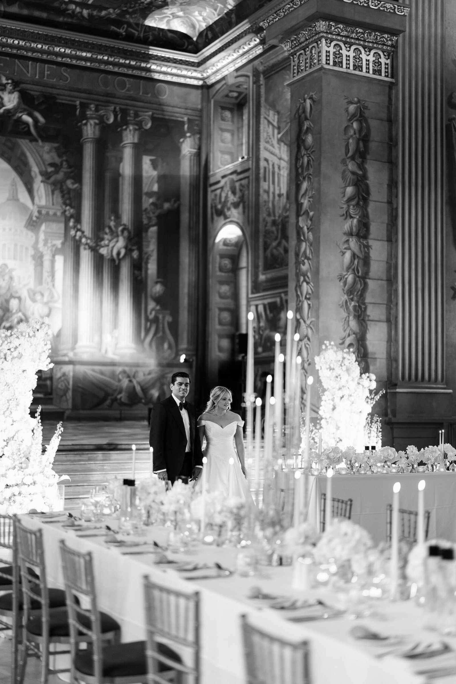 Black and white London wedding reception design inside an ornate historic hall with candlelight and long dining tables.