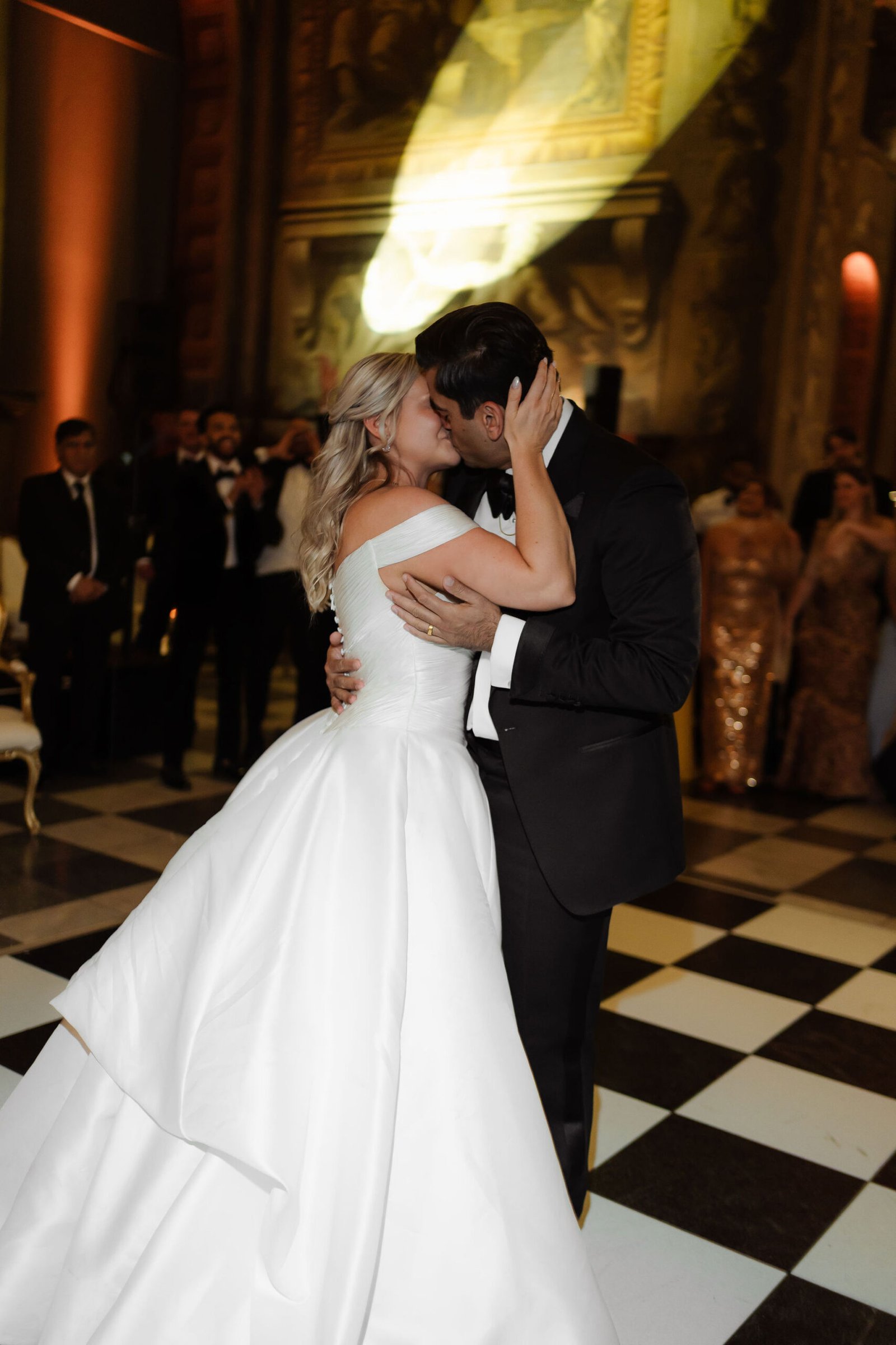 High-energy luxury wedding dance floor with guests celebrating inside an ornate reception venue.