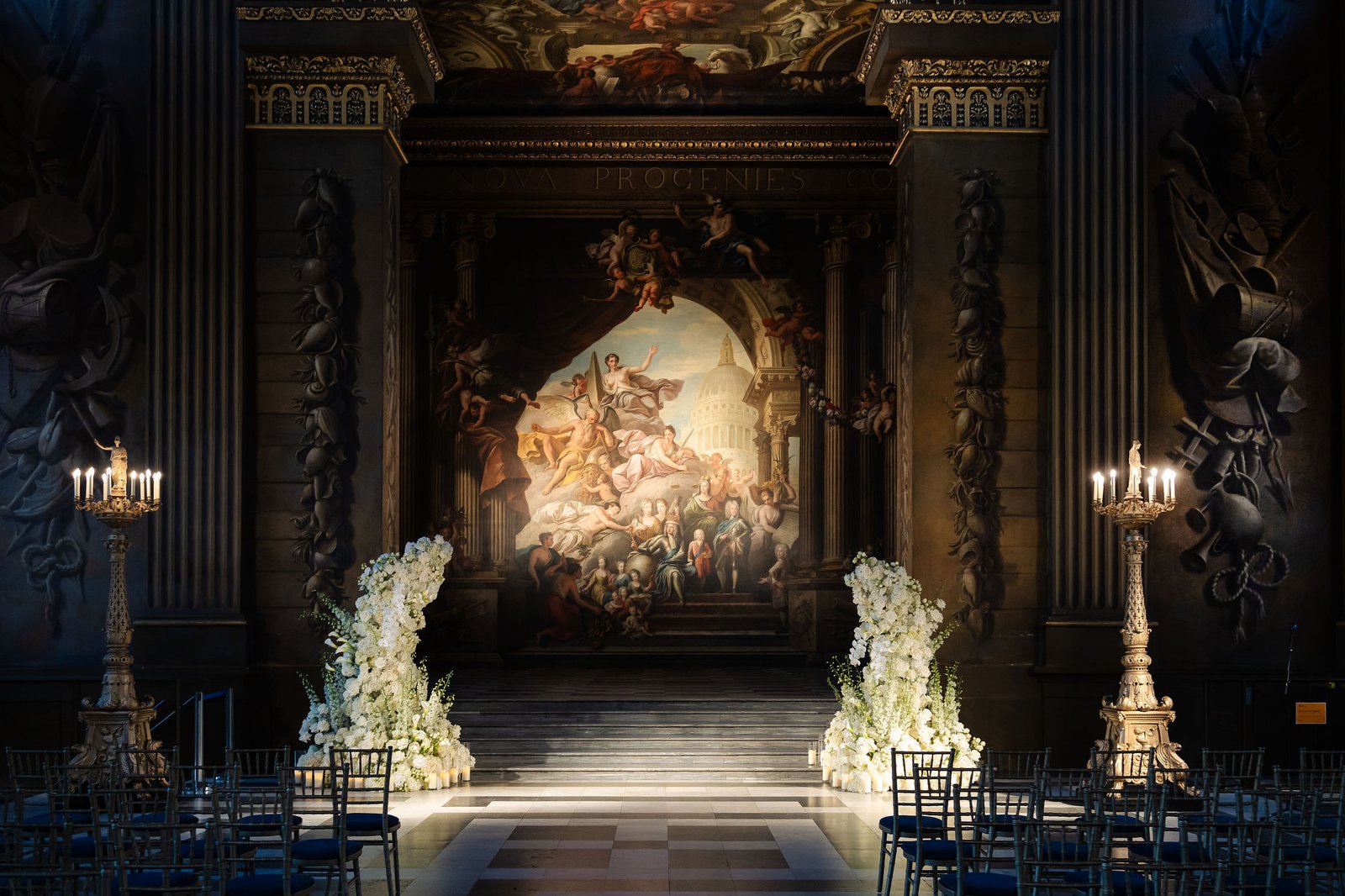 London wedding reception design inside an ornate historic hall with candlelight and long dining tables.