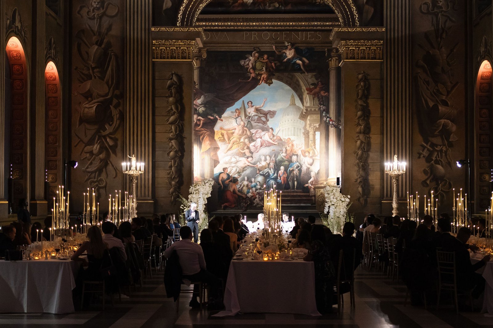 London wedding reception design inside an ornate historic hall with candlelight and long dining tables.