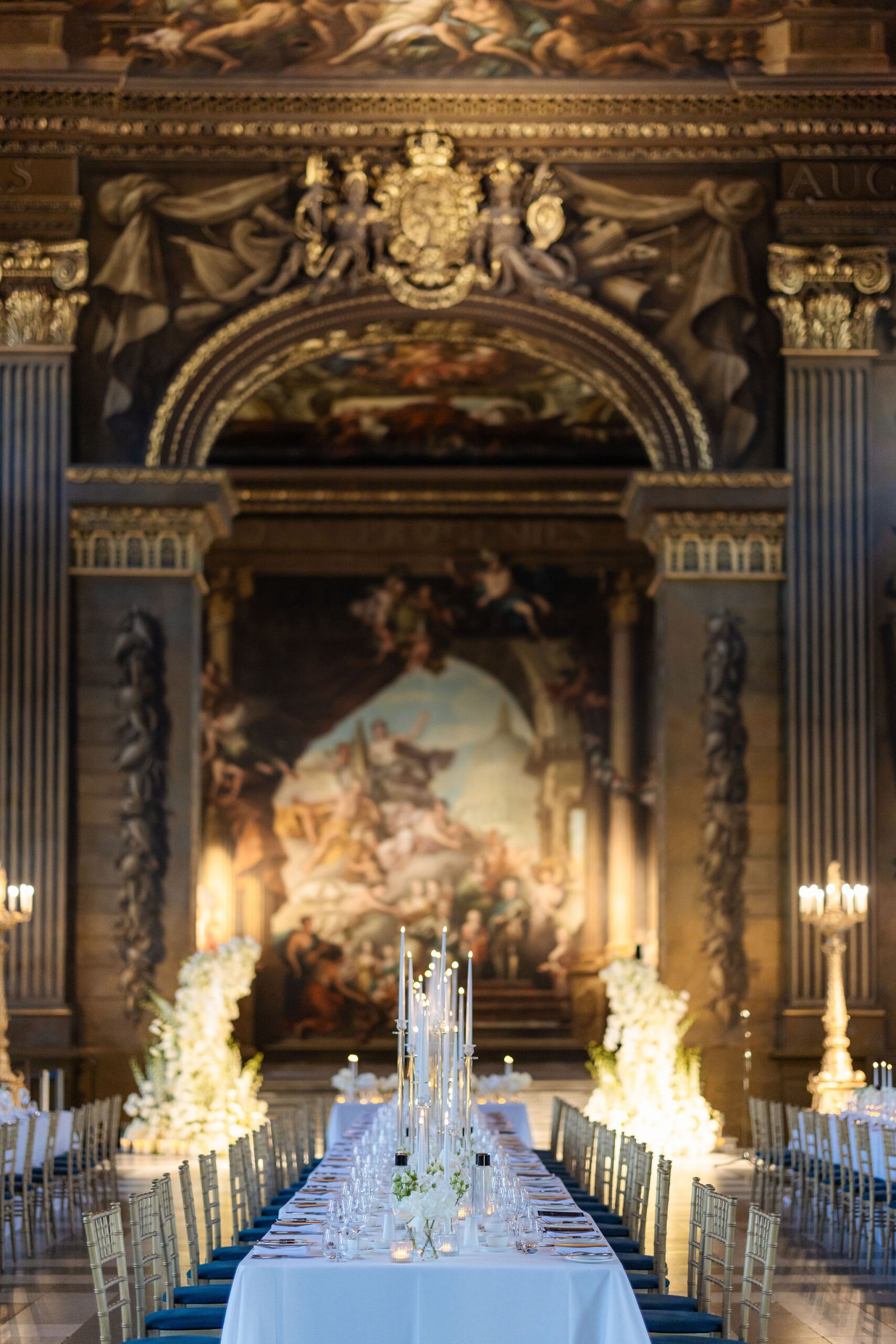 London wedding reception design inside an ornate historic hall with candlelight and long dining tables.