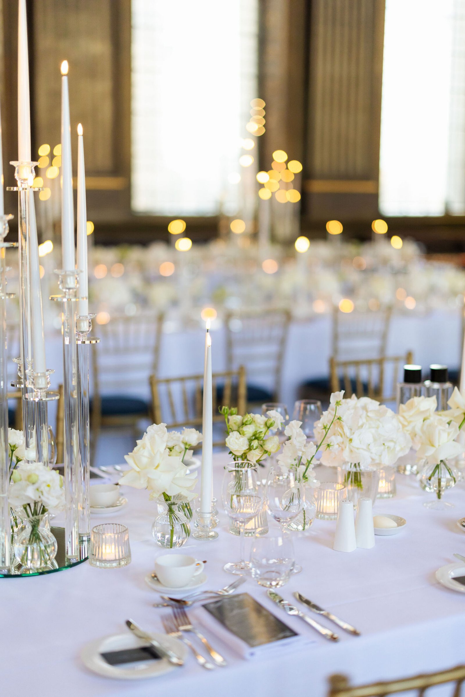 London wedding reception design inside an ornate historic hall with candlelight and long dining tables.