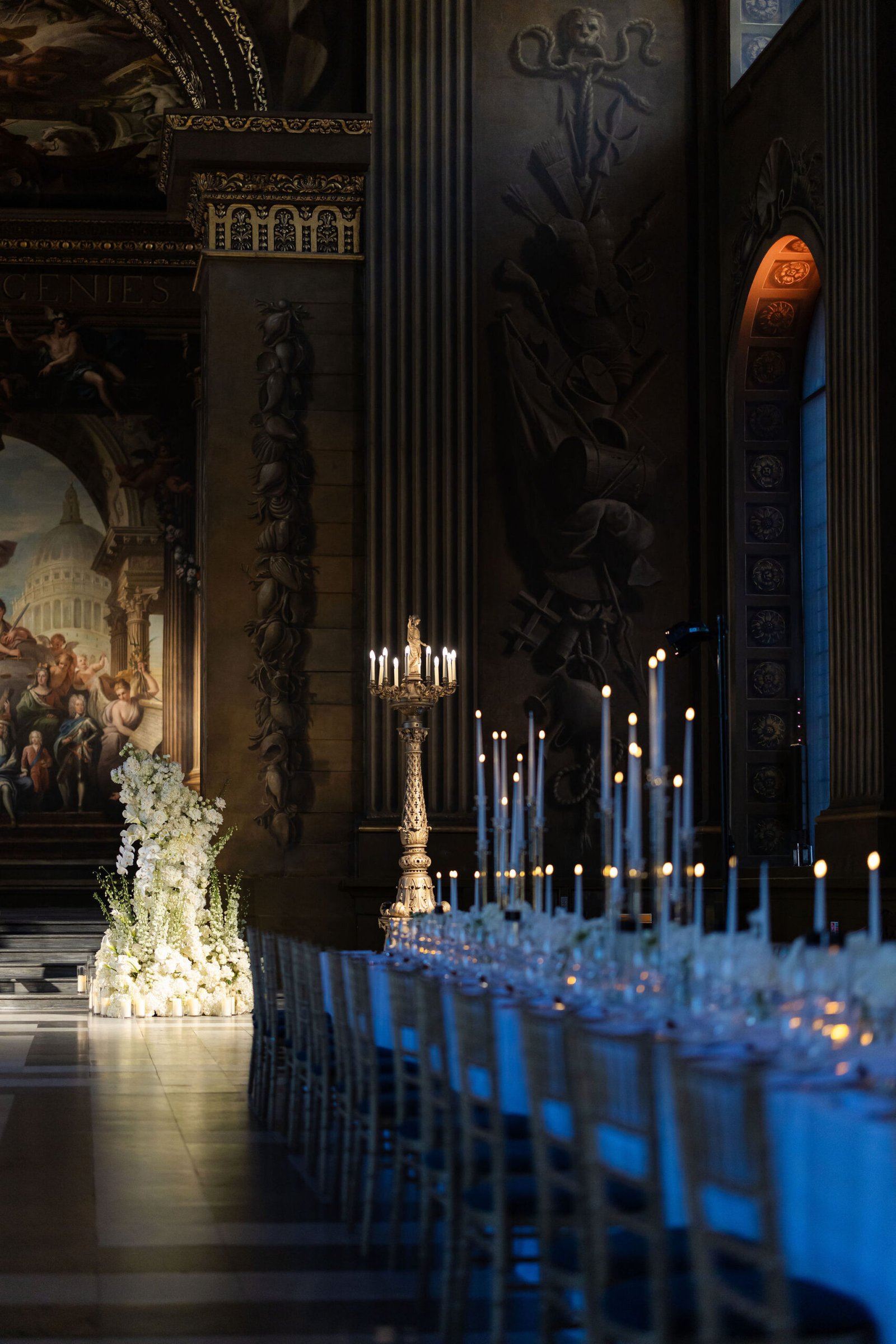 London wedding reception design inside an ornate historic hall with candlelight and long dining tables.