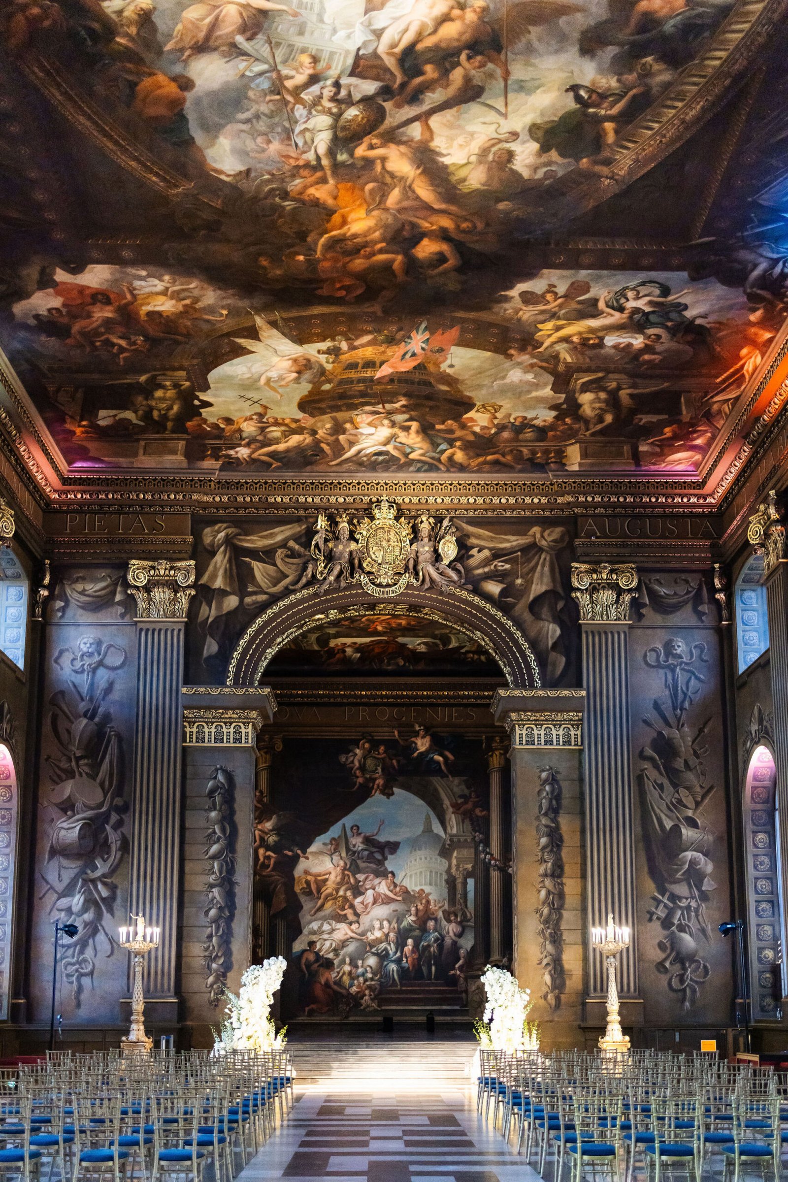 Ceremony seating and flowers beneath the painted ceiling of a historic London hall