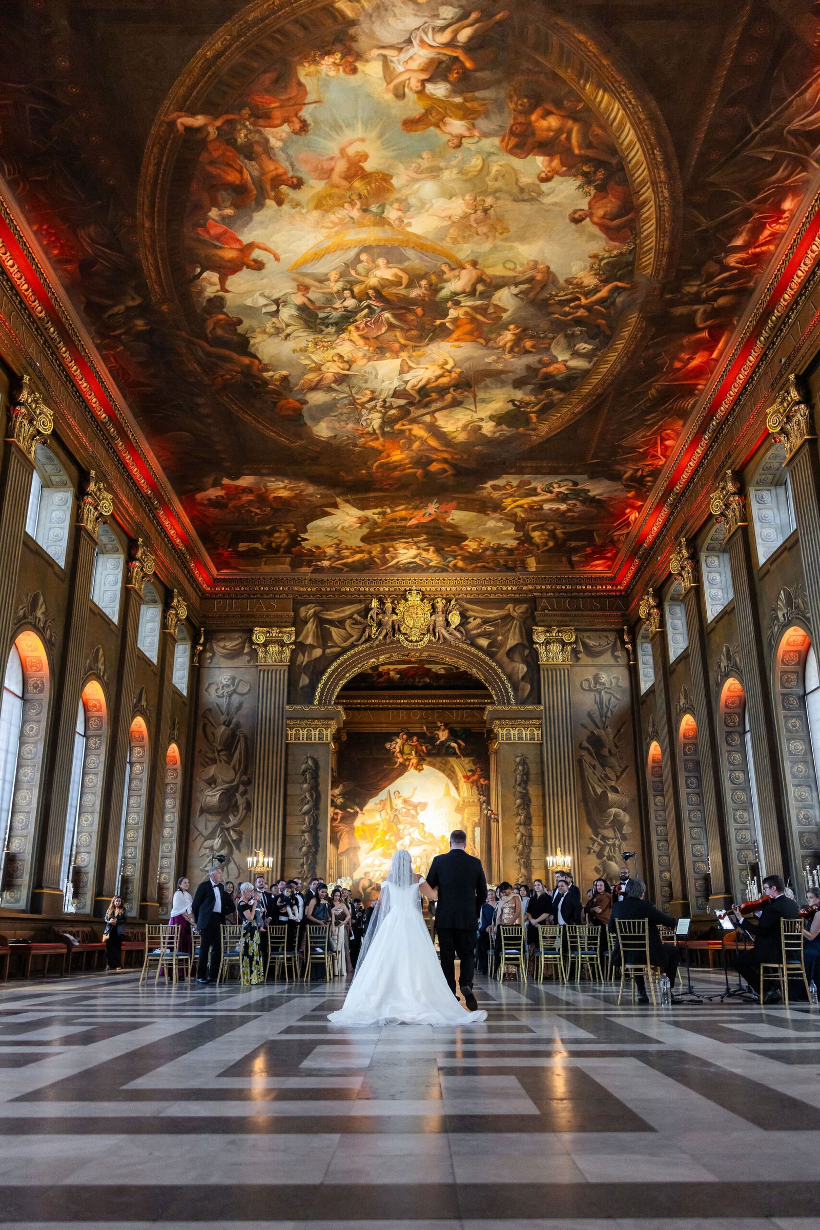 London wedding reception design inside an ornate historic hall with candlelight and long dining tables.