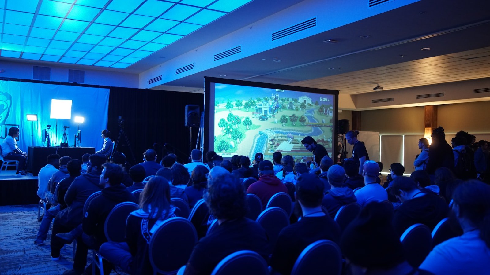 Conference guests watching a presentation in a room with blue stage lighting